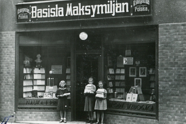 Witryna księgarni, przed nią stoją trzy dziewczynki